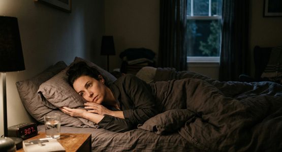 Woman lying awake at 3am staring at alarm clock, insomnia hypnotherapy Calgary